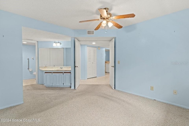 spare room with a textured ceiling, ceiling fan, light colored carpet, and sink