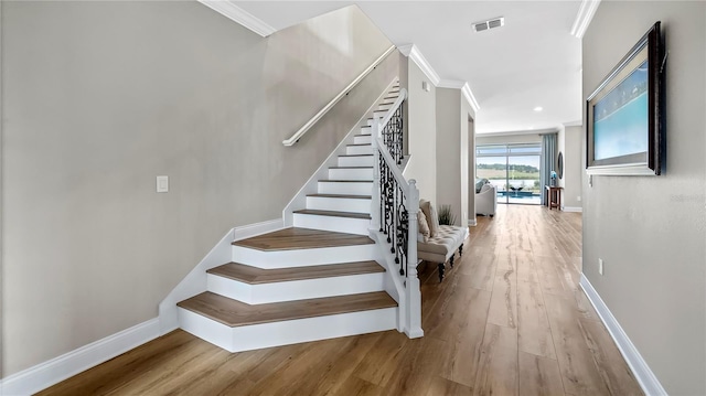 stairway featuring ornamental molding and hardwood / wood-style floors