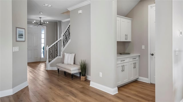 hallway featuring a chandelier, ornamental molding, and light hardwood / wood-style flooring