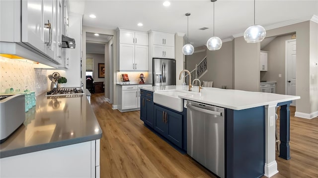 kitchen with appliances with stainless steel finishes, white cabinetry, blue cabinetry, and sink