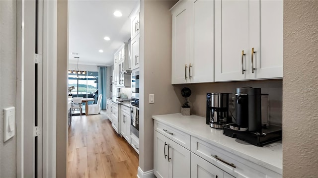 kitchen featuring white cabinets, light wood-type flooring, and light stone counters