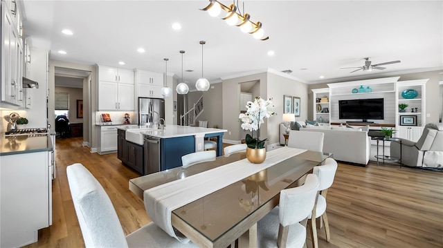 dining space with ceiling fan, crown molding, sink, and hardwood / wood-style flooring