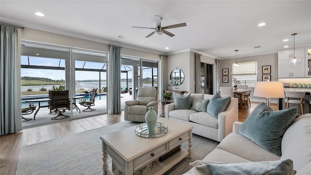 living room with ceiling fan, light wood-type flooring, a water view, and a wealth of natural light