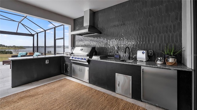 kitchen featuring sink, tasteful backsplash, light tile patterned floors, stainless steel fridge, and wall chimney range hood