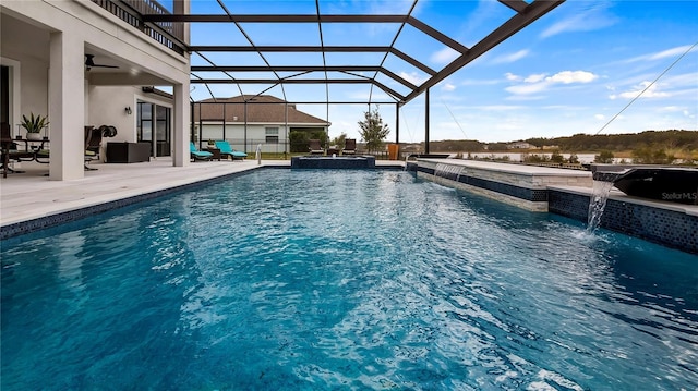 view of pool with an in ground hot tub, a patio, ceiling fan, glass enclosure, and pool water feature