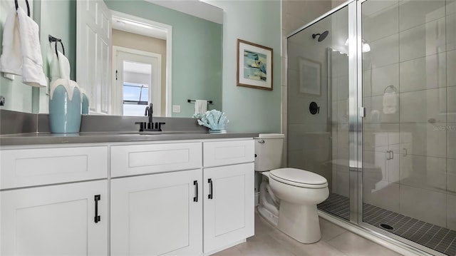 bathroom featuring vanity, a shower with door, tile patterned flooring, and toilet