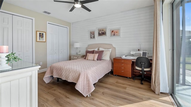 bedroom featuring access to outside, ceiling fan, light hardwood / wood-style flooring, and multiple closets