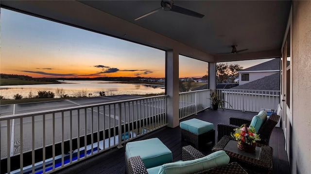 balcony at dusk featuring ceiling fan, a water view, and outdoor lounge area