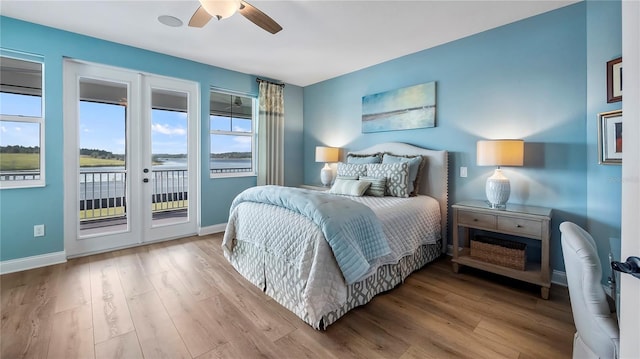 bedroom with a water view, ceiling fan, french doors, light hardwood / wood-style flooring, and access to outside