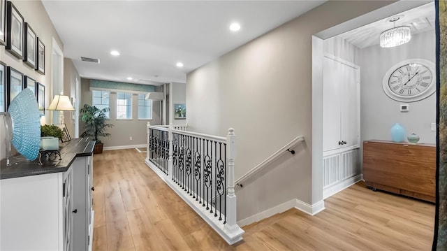 hallway with an inviting chandelier and light hardwood / wood-style floors