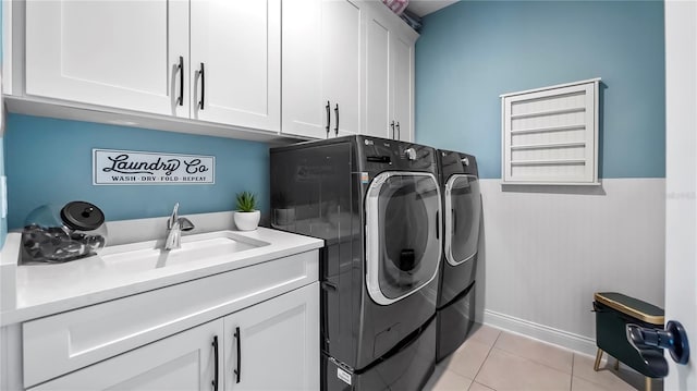 clothes washing area with washer and dryer, sink, light tile patterned floors, and cabinets