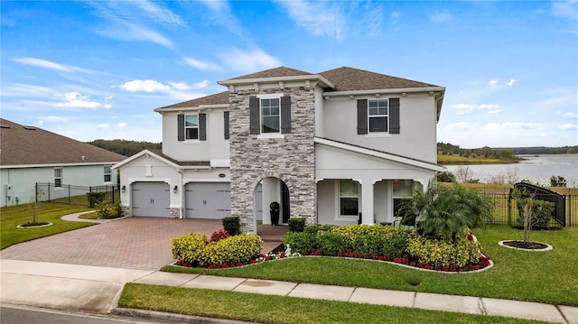 view of front of home featuring a front yard, a garage, and a water view