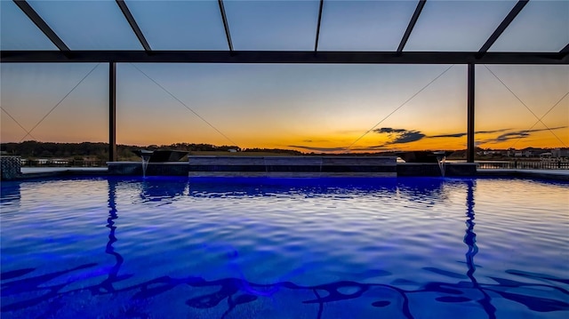 pool at dusk with pool water feature and glass enclosure