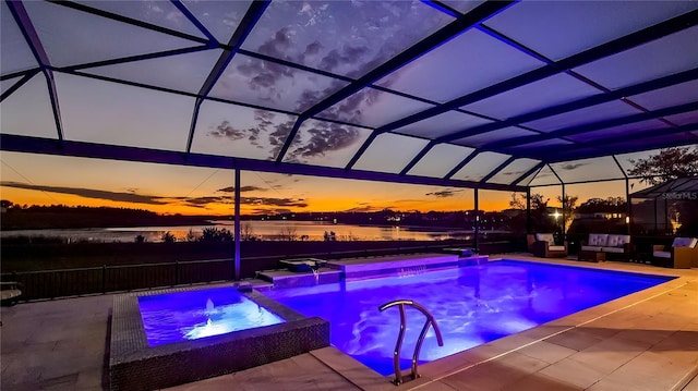 pool at dusk with a patio, glass enclosure, pool water feature, an in ground hot tub, and a water view