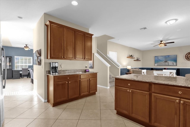 kitchen with ceiling fan, light stone counters, and light tile patterned floors