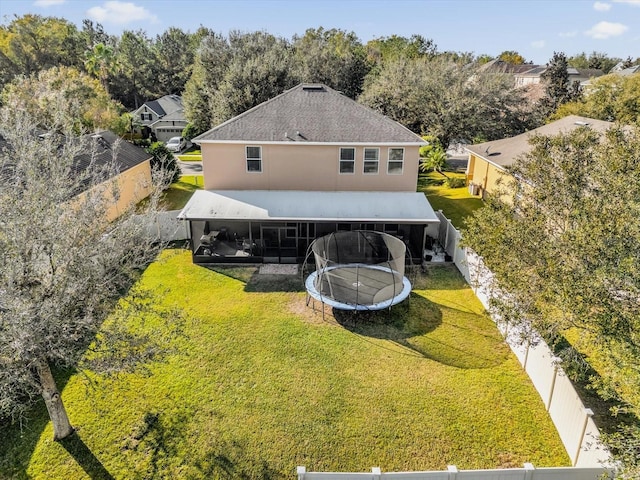 rear view of house with a yard and a trampoline