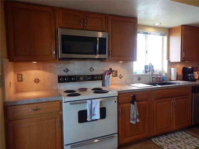 kitchen featuring light tile patterned flooring, appliances with stainless steel finishes, backsplash, and sink