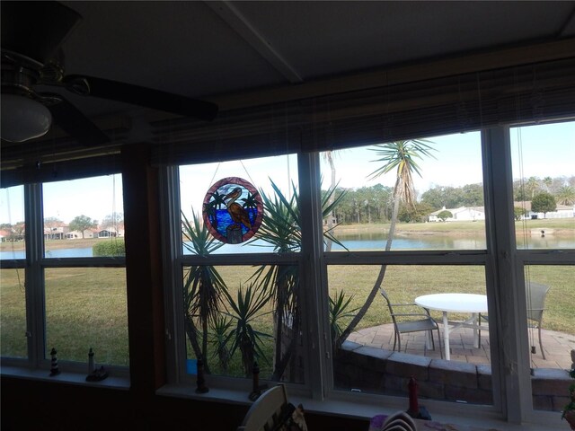 sunroom with ceiling fan and a water view