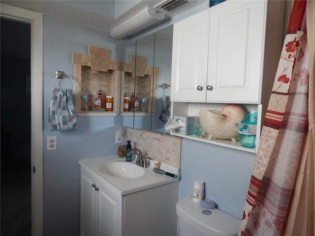 bathroom featuring vanity, toilet, and backsplash