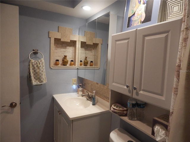 bathroom featuring vanity, toilet, and backsplash