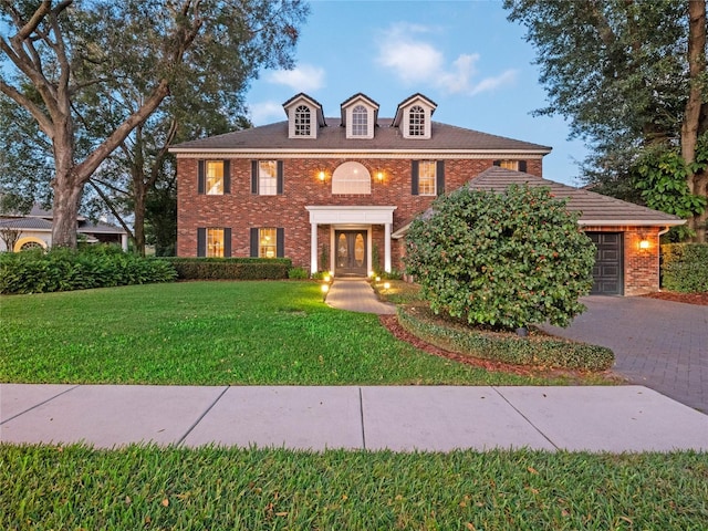 colonial-style house featuring french doors, a garage, and a front lawn