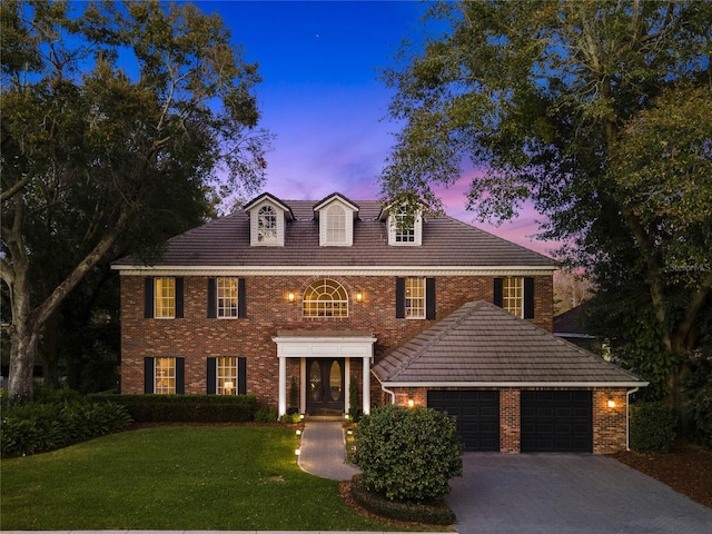 colonial inspired home featuring a garage and a yard