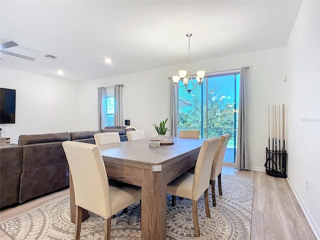 dining space with light hardwood / wood-style floors and a chandelier