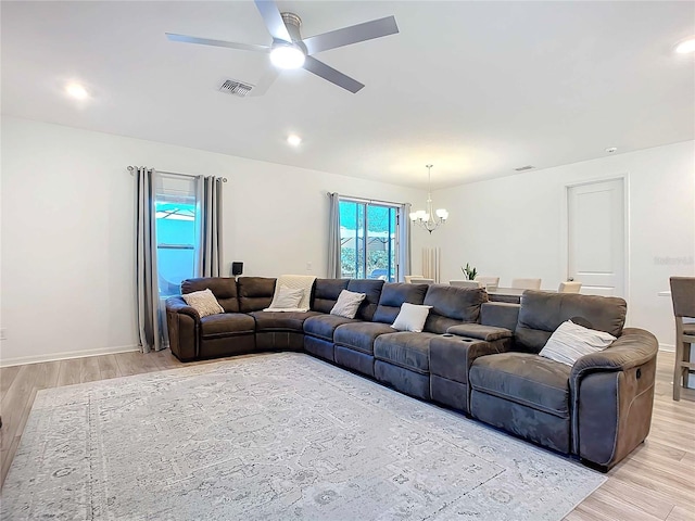 living room featuring ceiling fan with notable chandelier and light hardwood / wood-style floors