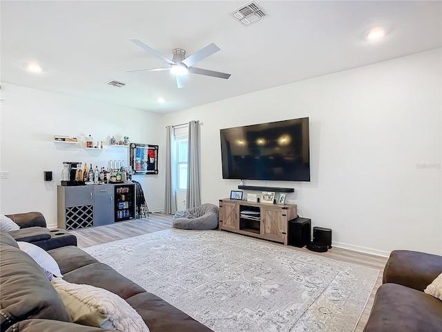 living room featuring hardwood / wood-style floors, ceiling fan, and indoor bar