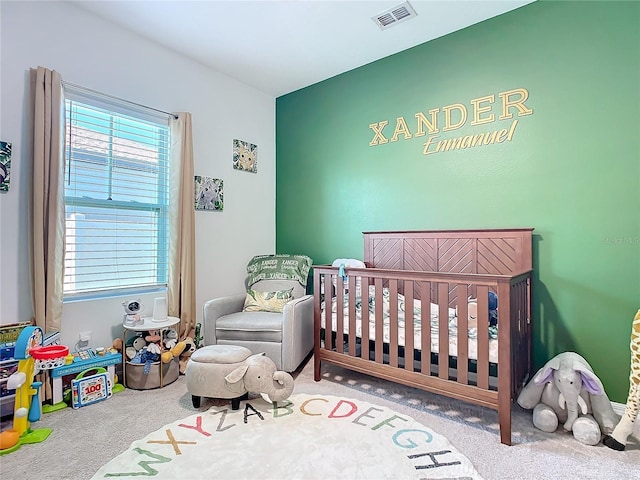 bedroom with a nursery area and carpet flooring