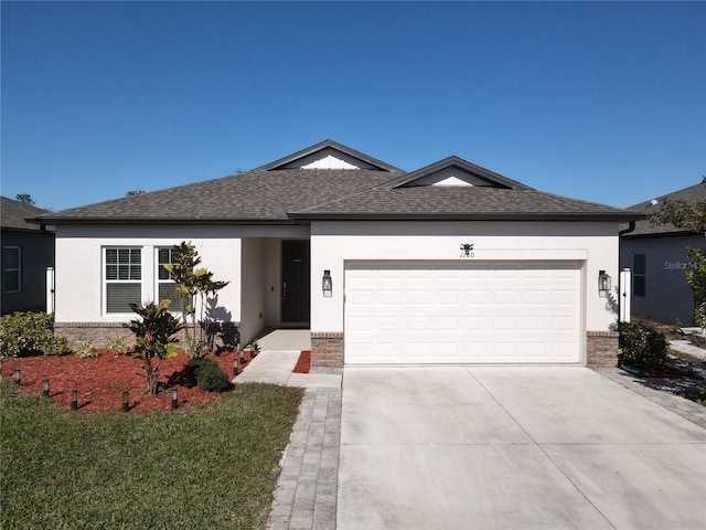 ranch-style home with a shingled roof, concrete driveway, brick siding, and stucco siding