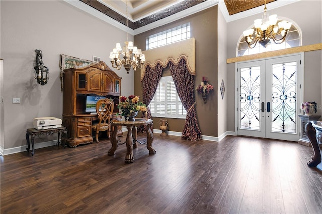 foyer with french doors, dark hardwood / wood-style flooring, ornamental molding, an inviting chandelier, and a high ceiling