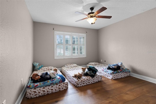 bedroom with ceiling fan, dark hardwood / wood-style floors, and a textured ceiling