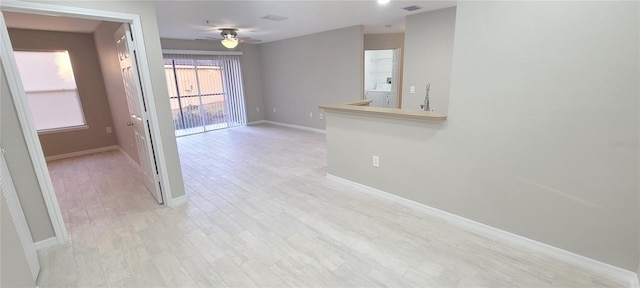 unfurnished room with washer / clothes dryer, ceiling fan, and light wood-type flooring