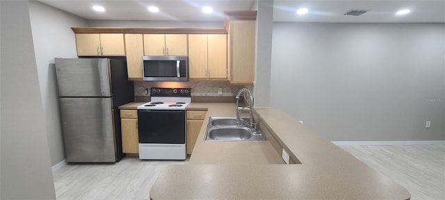 kitchen featuring sink, stainless steel appliances, light hardwood / wood-style floors, light brown cabinetry, and decorative backsplash