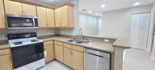 kitchen with appliances with stainless steel finishes, kitchen peninsula, sink, and light brown cabinets