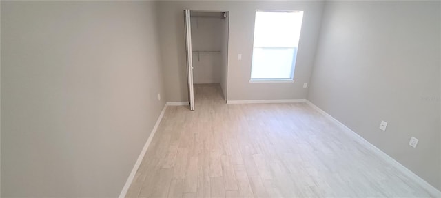 unfurnished bedroom with a spacious closet, a closet, and light wood-type flooring