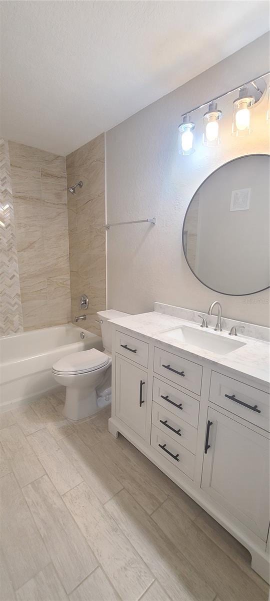 full bathroom featuring vanity, a textured ceiling, toilet, and tiled shower / bath