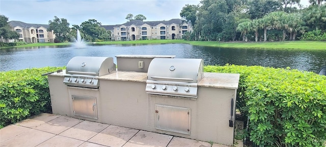 view of patio / terrace with a water view, an outdoor kitchen, and a grill