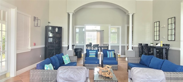 tiled living room featuring ornate columns and a towering ceiling