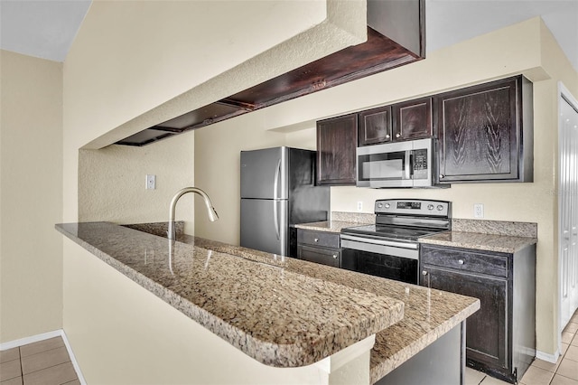 kitchen with light stone counters, appliances with stainless steel finishes, kitchen peninsula, and light tile patterned flooring