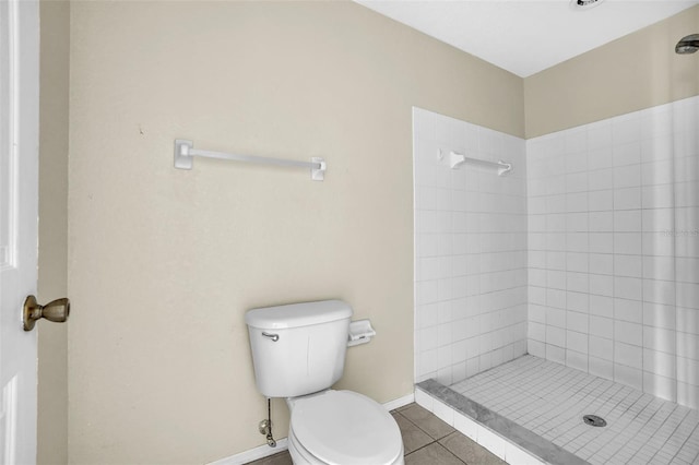 bathroom featuring toilet, a tile shower, and tile patterned flooring