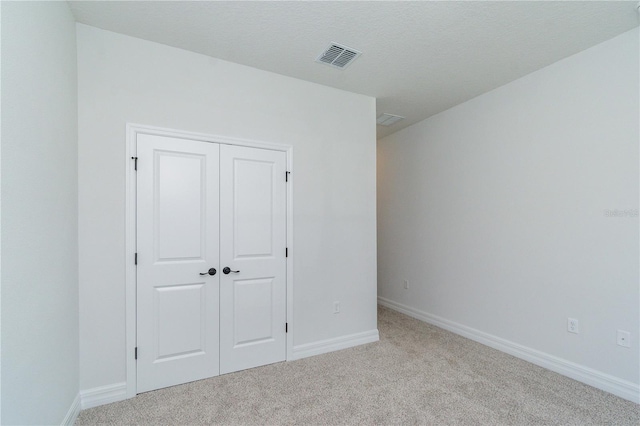 unfurnished bedroom featuring baseboards, a closet, visible vents, and carpet flooring