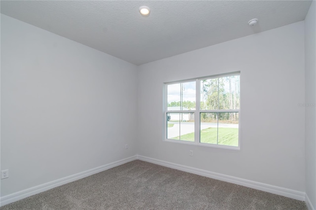 unfurnished room featuring a textured ceiling, carpet flooring, and baseboards