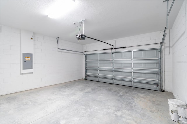 garage featuring concrete block wall, electric panel, and a garage door opener