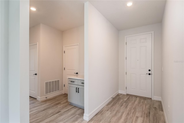 hallway with light wood-type flooring, visible vents, baseboards, and recessed lighting