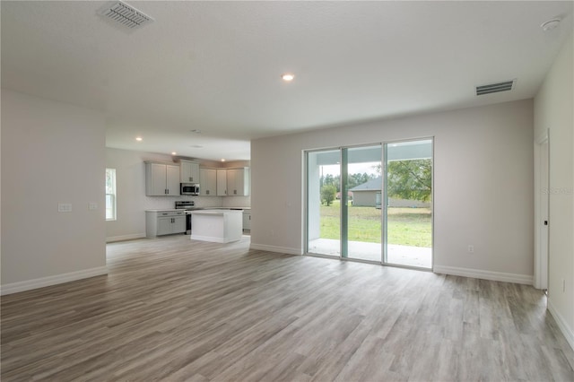 unfurnished living room with visible vents, light wood-style flooring, and baseboards