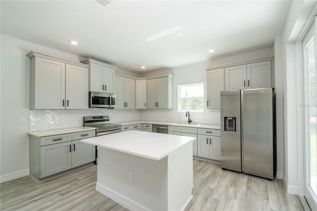 kitchen with stainless steel appliances, a sink, and gray cabinetry