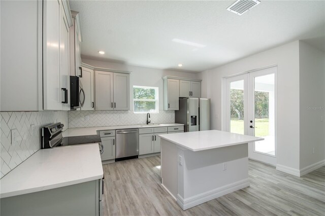 kitchen featuring stainless steel appliances, a kitchen island, a sink, visible vents, and backsplash