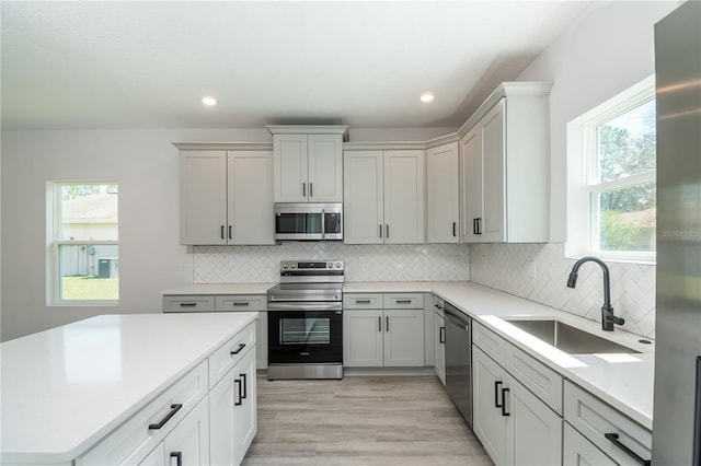 kitchen with stainless steel appliances, a healthy amount of sunlight, a sink, and backsplash